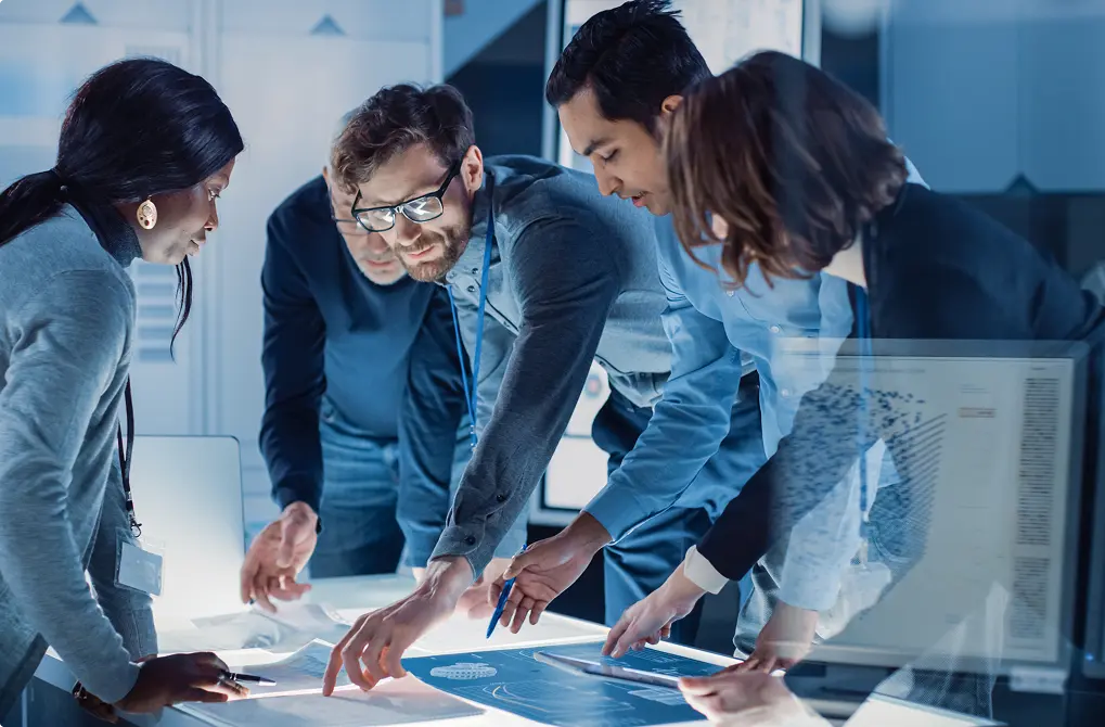 People around a desk pointing at graphs
